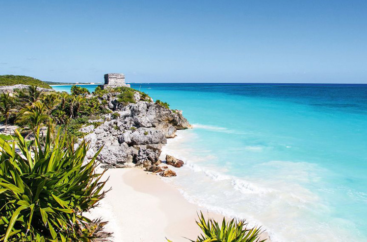 Beautiful beach with turquoise water  in Tulum Mexico, Mayan ruins on top of the cliff.