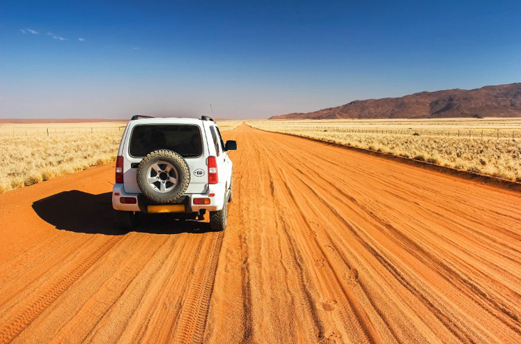 Car on straight lonely sand pad, Namibia