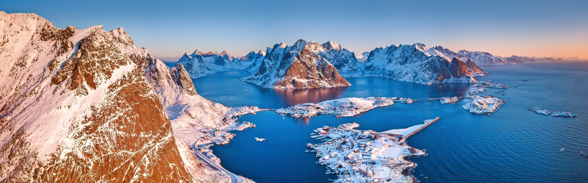 Aerial panoramic view of amazing Lofoten Islands winter scenery with famous Reine fishing village in beautiful golden morning light at sunrise, Norway, Scandinavia.