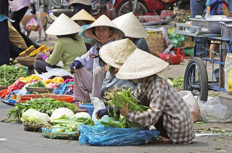 Women in conical hats selling vegetables sitting on street Binh Tay Market Cholon Ho Chi Minh City Vietnam